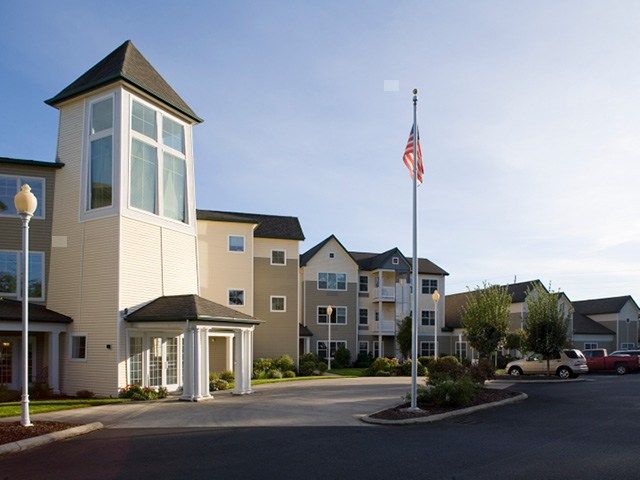 A residential building with a flagpole in front, seen during the daytime.