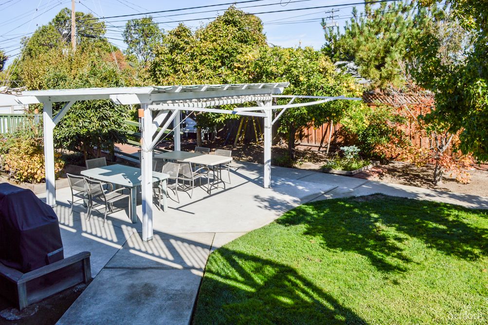 A sunny backyard with a pergola and outdoor seating area.