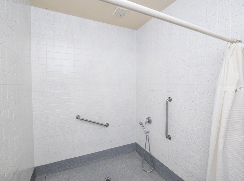 An accessible shower area with grab bars and tiled walls.