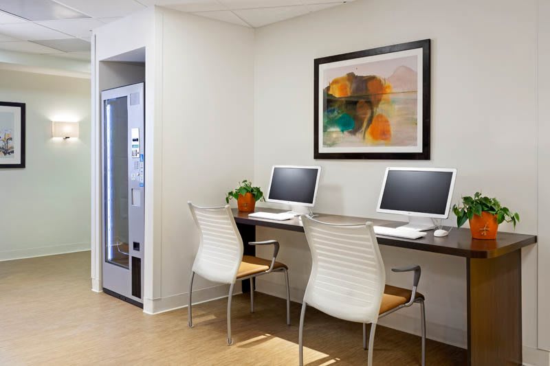 A modern office workspace featuring two computers and chairs, with abstract artwork on the wall.