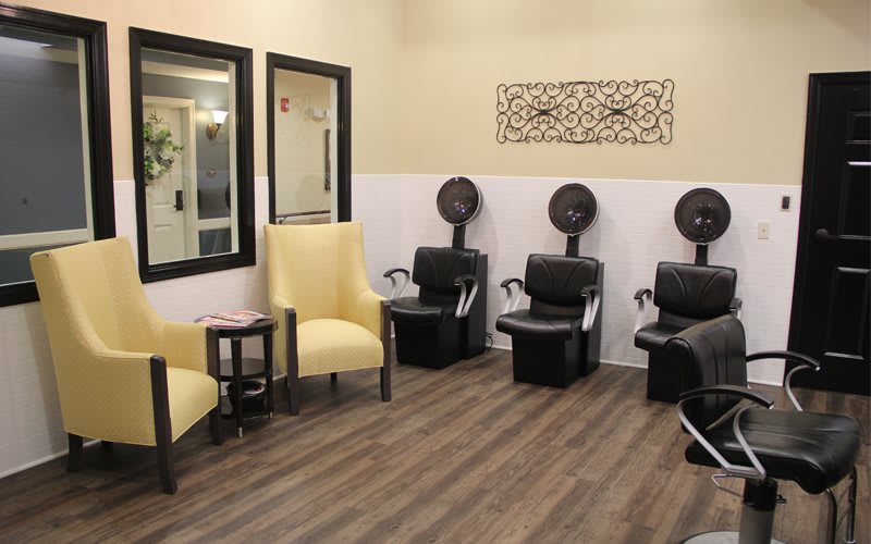 Interior view of a hair salon featuring chairs, mirrors, and hair dryers.