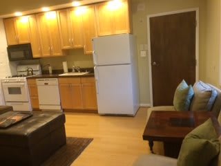 Open-concept kitchen and living area in an apartment with wood cabinetry and modern appliances.