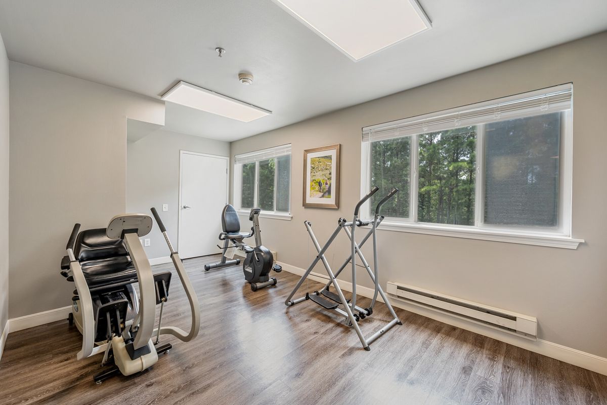 A bright and spacious home gym featuring various exercise equipment including a treadmill, elliptical machine, and exercise bike.