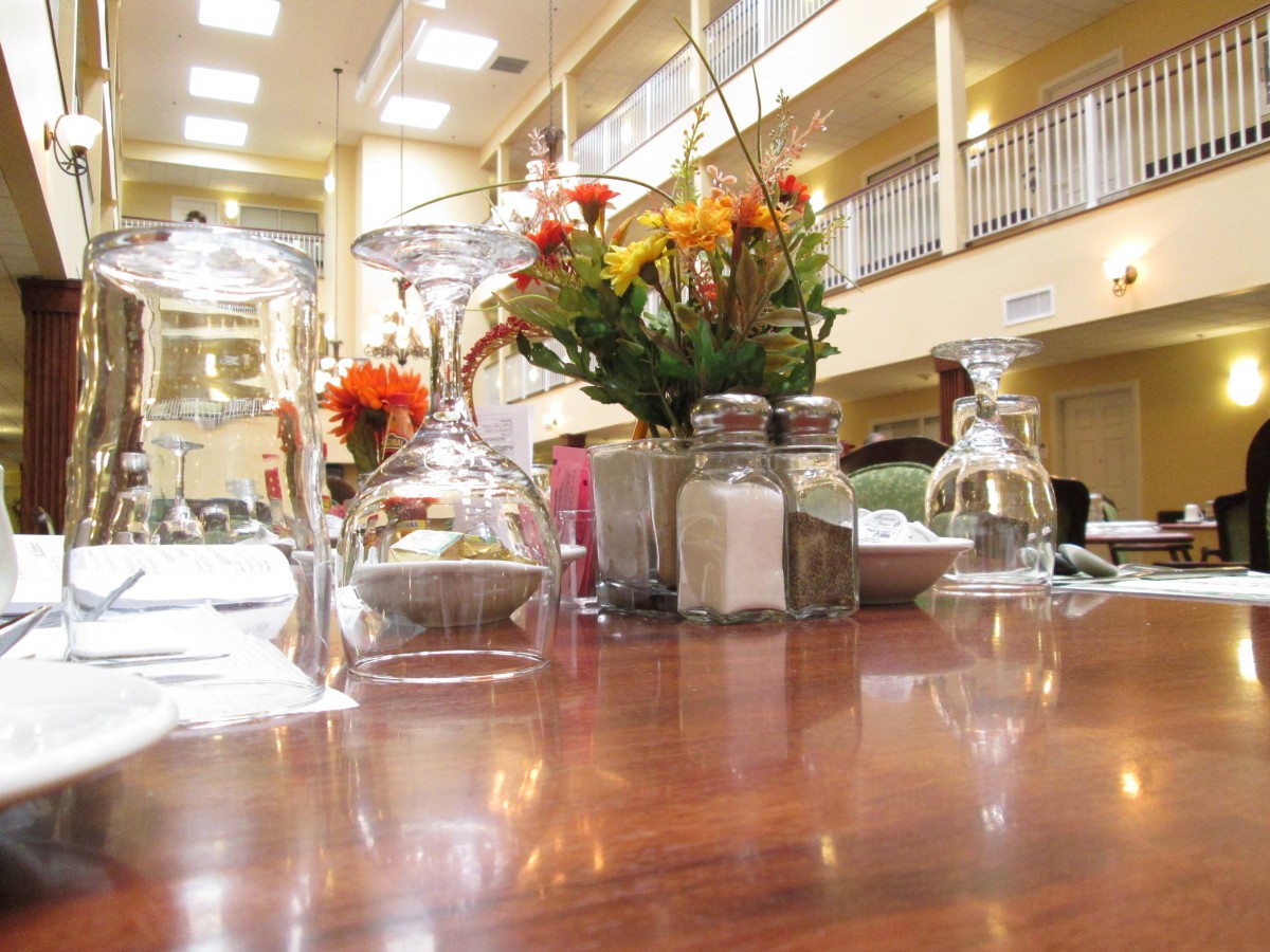 A well-set restaurant table with glassware, flowers, and salt and pepper shakers in an elegant dining area.