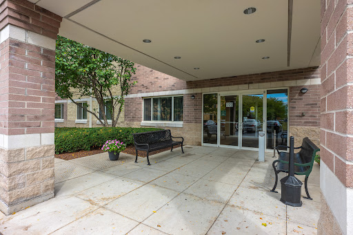 A welcoming entrance featuring benches and landscaped greenery.