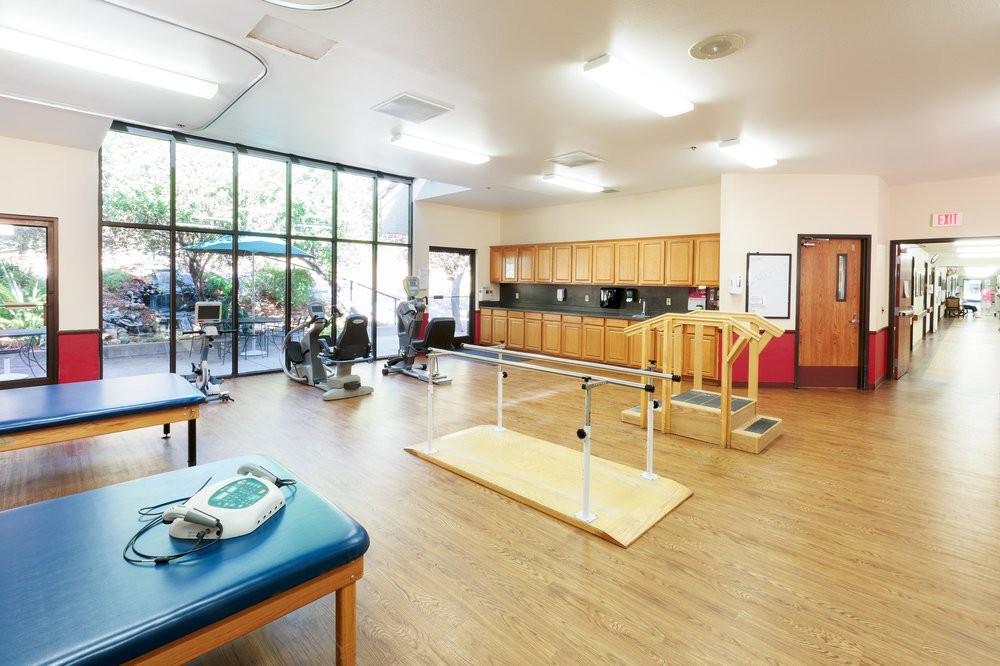 A well-equipped physical therapy and rehabilitation room with exercise equipment and parallel bars.