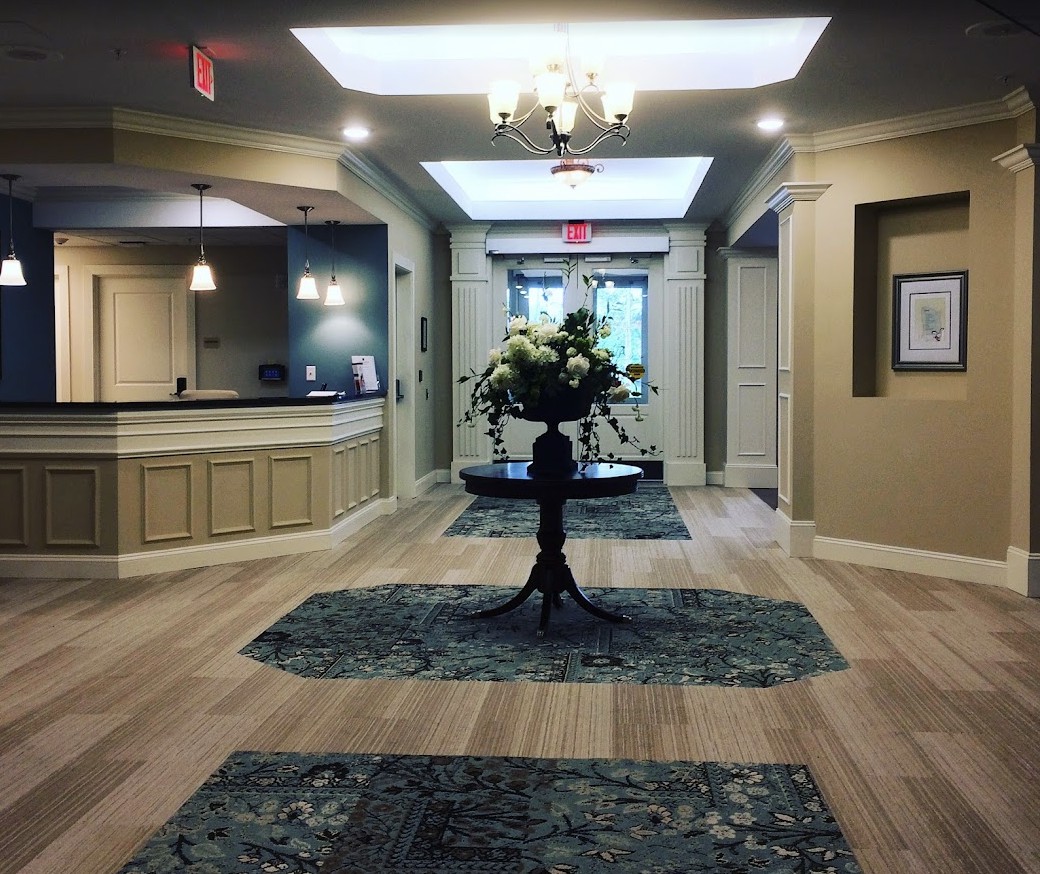A modern lobby with elegant interior design, featuring a floral arrangement and chandeliers.