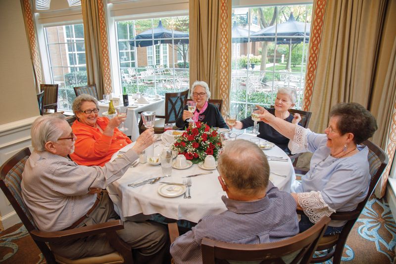 A group of elderly people enjoying a meal together at a decorated dining table.