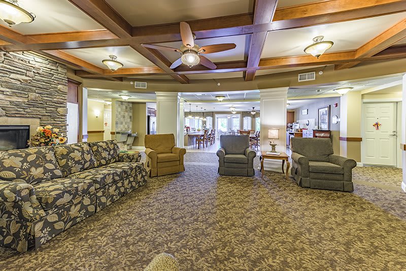 Cozy living room with sofas and armchairs, featuring a ceiling fan and warm lighting.