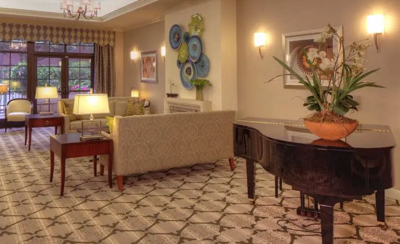 A cozy living room with a grand piano, elegant furniture, and decorative artwork.