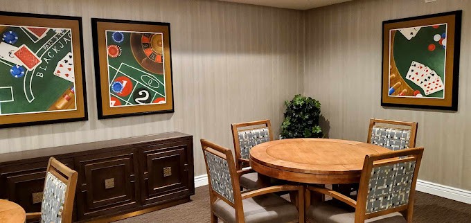 A cozy room with a round table, chairs, artwork on the wall, and a cabinet.