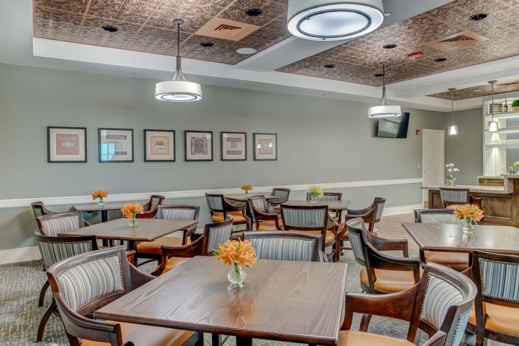 A cozy dining area with neatly arranged tables and comfortable chairs, featuring modern lighting and wall decorations.