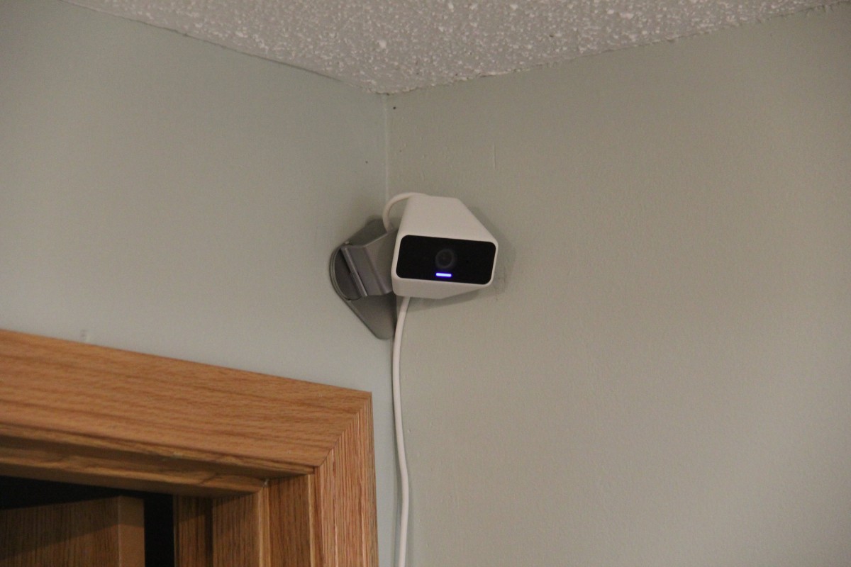 An indoor, wall-mounted security camera is positioned in the corner of a room.
