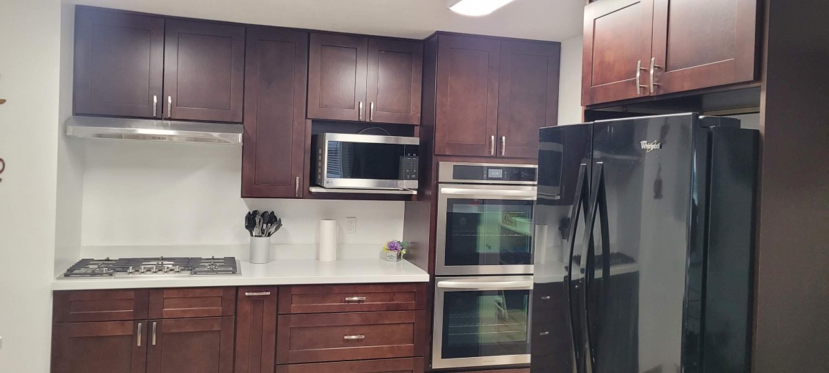 Modern kitchen with dark wood cabinets and stainless steel appliances.