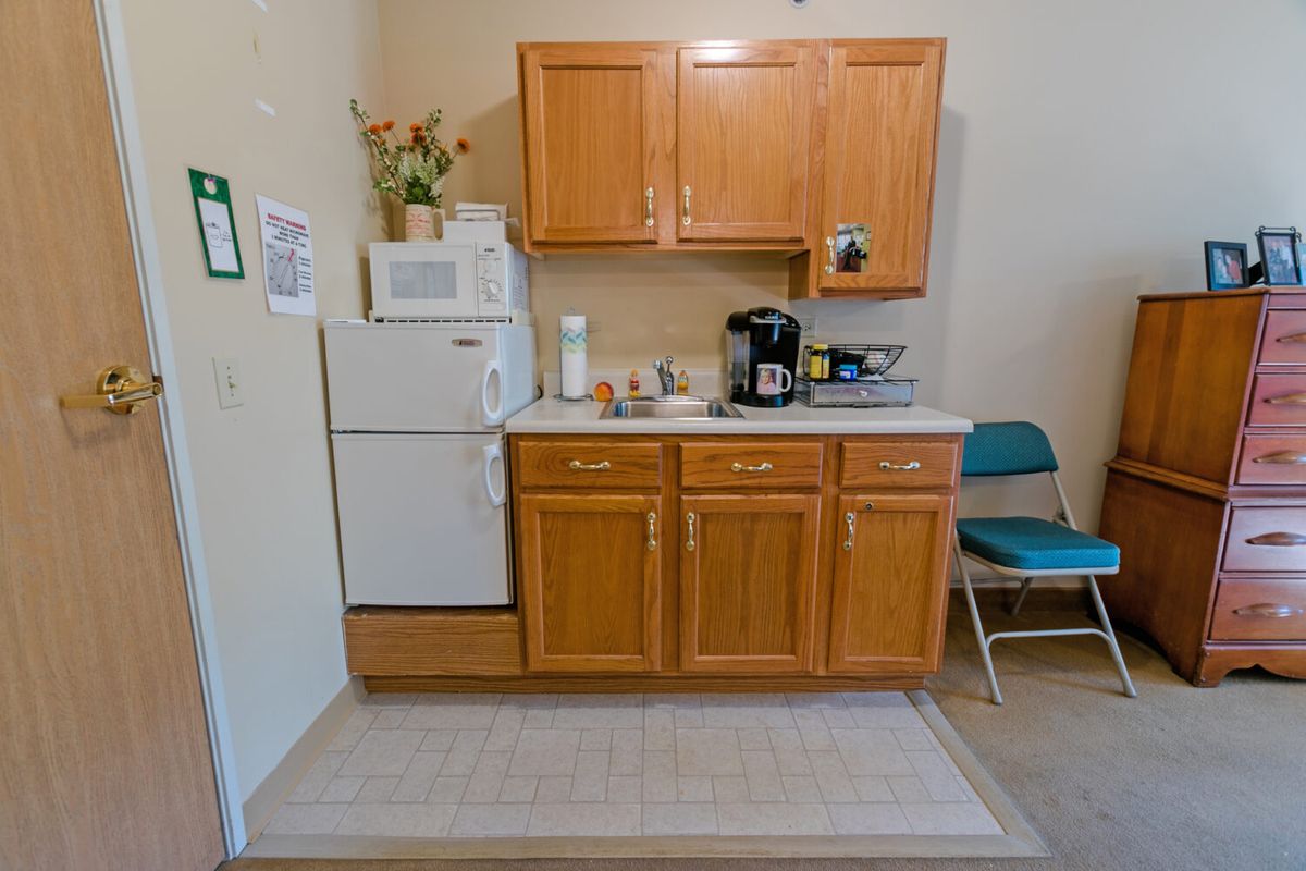 A compact kitchen setup with wooden cabinets, a microwave, coffee maker, and refrigerator.