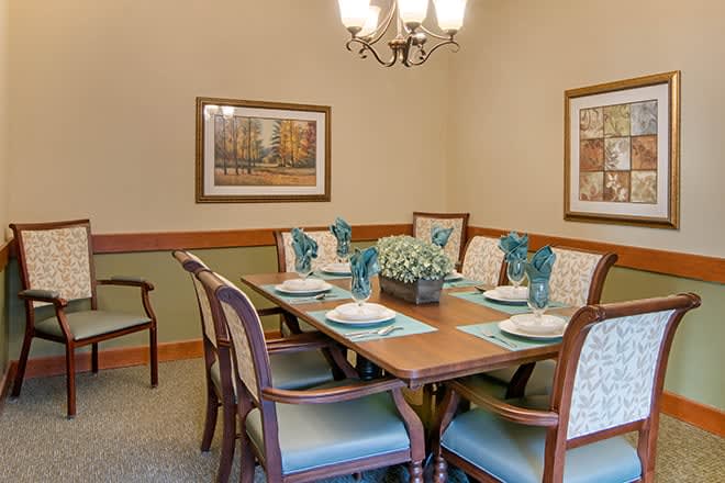 A traditional dining room setup with a wooden table, upholstered chairs, and decorative place settings.