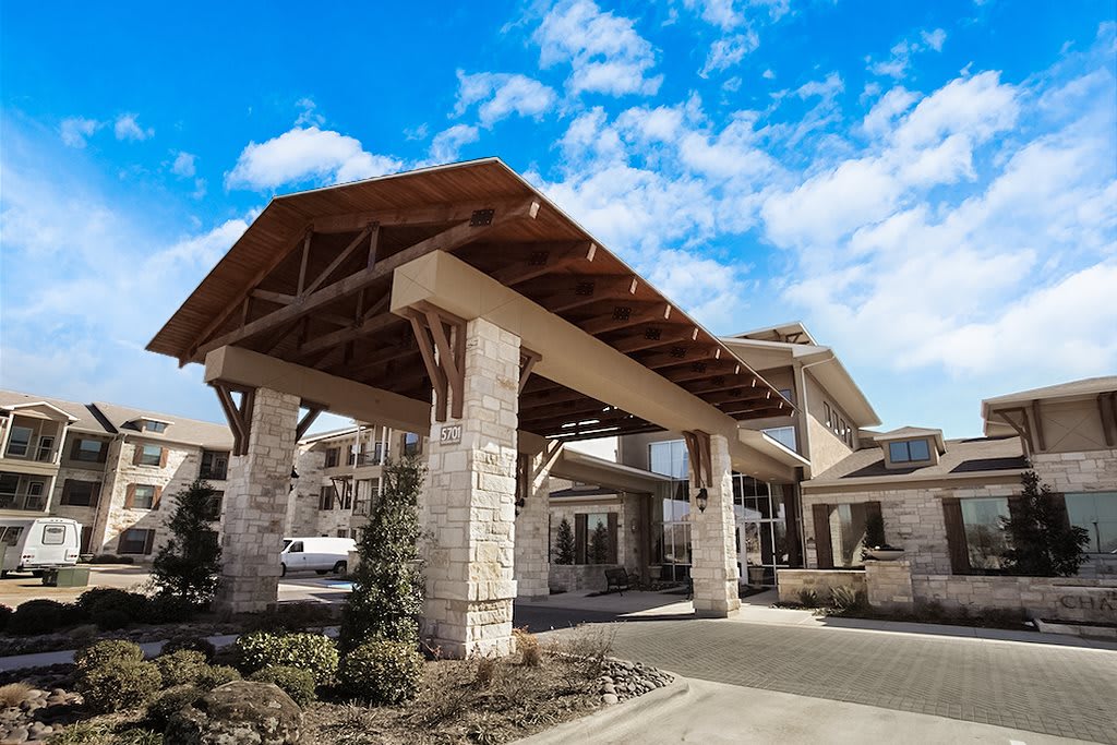 A modern building entrance featuring wooden and stone architecture under a blue sky.