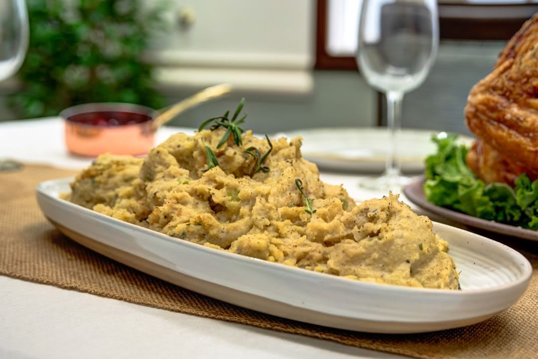 A plate of creamy mashed potatoes garnished with herbs, ready to be served at a dinner table.