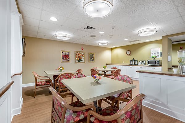 A cozy dining area with neatly arranged tables and chairs, adorned with simple decor and warm lighting.