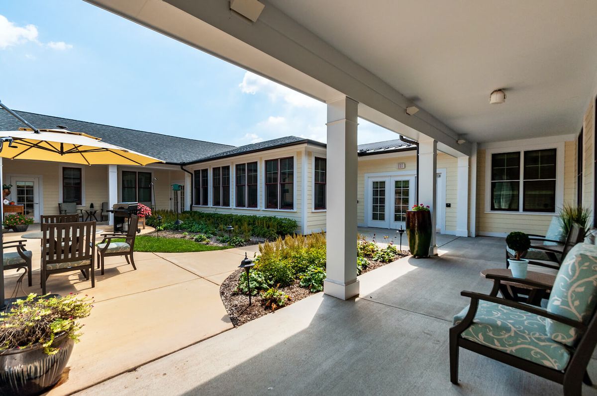 A serene courtyard with benches and outdoor seating, surrounded by a garden and framed by a building's columns.