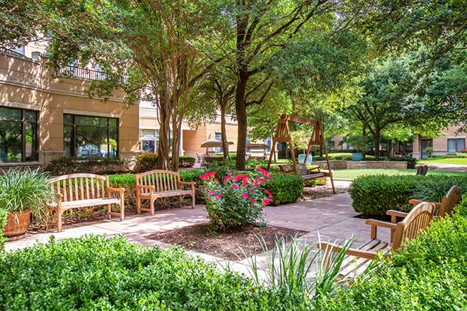 A serene garden with benches, surrounded by greenery and trees.