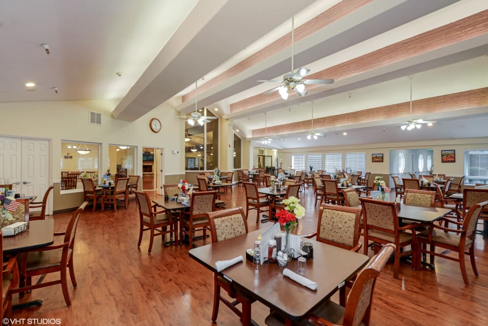 A spacious dining area with neatly arranged tables and chairs, featuring elegant decor and ample lighting.
