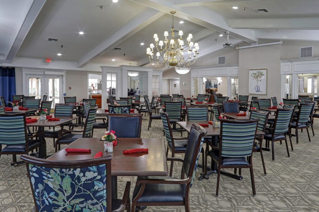 An elegant dining area with neatly arranged tables and chairs under a chandelier.