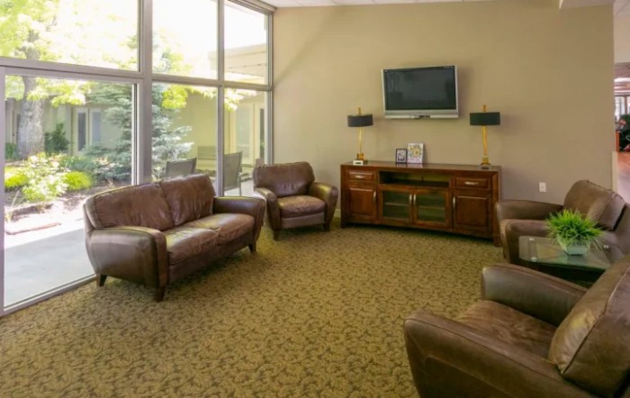 A cozy living room with leather seating and a wall-mounted TV.