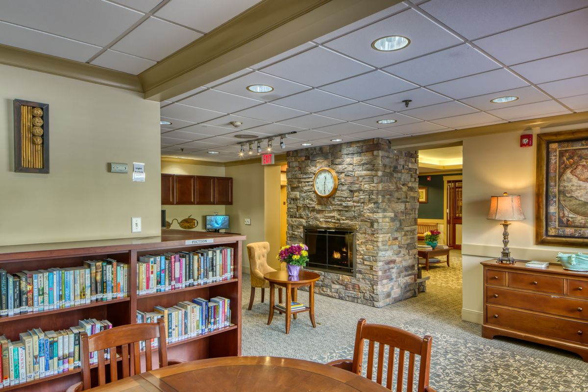A cozy library reading area with bookshelves and a fireplace.