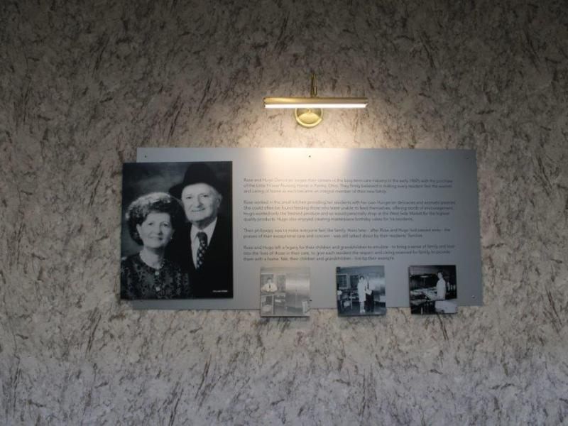 A historical plaque featuring a black and white photograph of a couple, accompanied by descriptive text and additional small images, illuminated by overhead lighting.