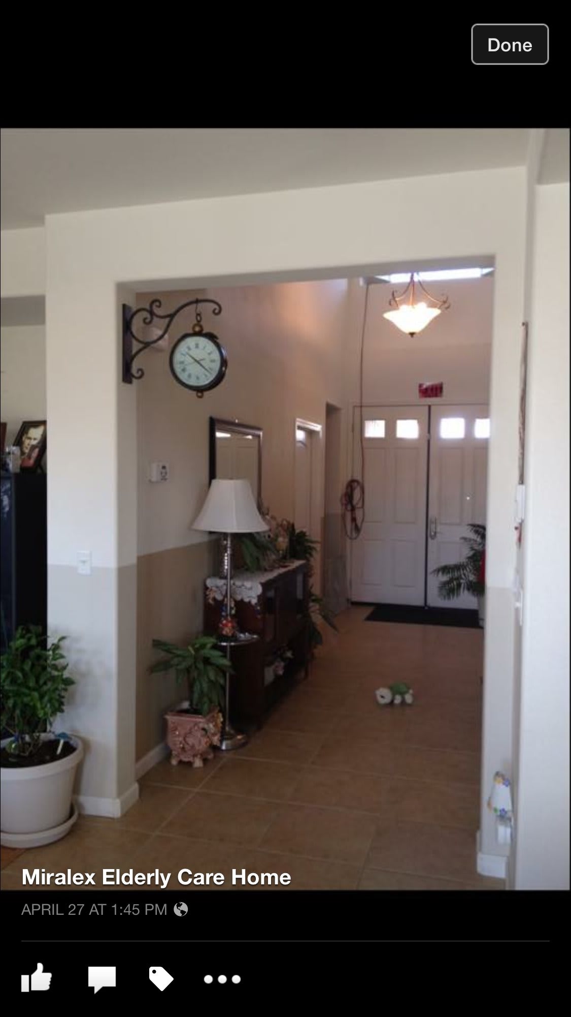 A well-decorated hallway with a wall clock, table lamp, plants, and furniture.