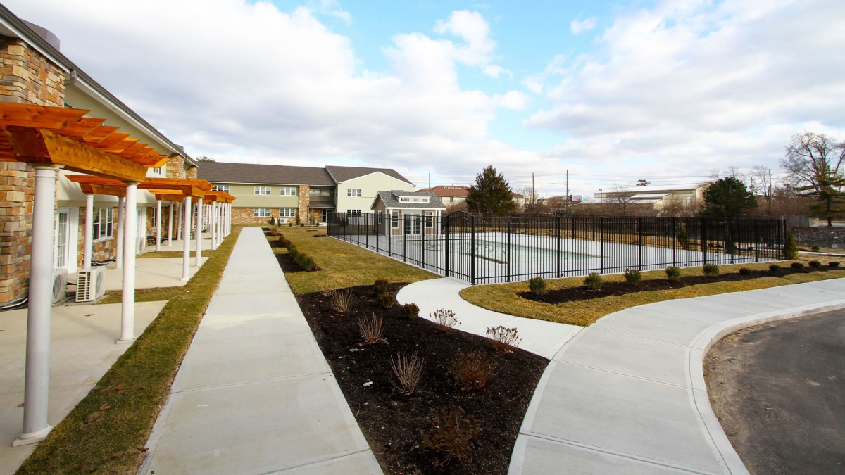 A view of outdoor tennis courts surrounded by pathways and buildings under a partly cloudy sky.