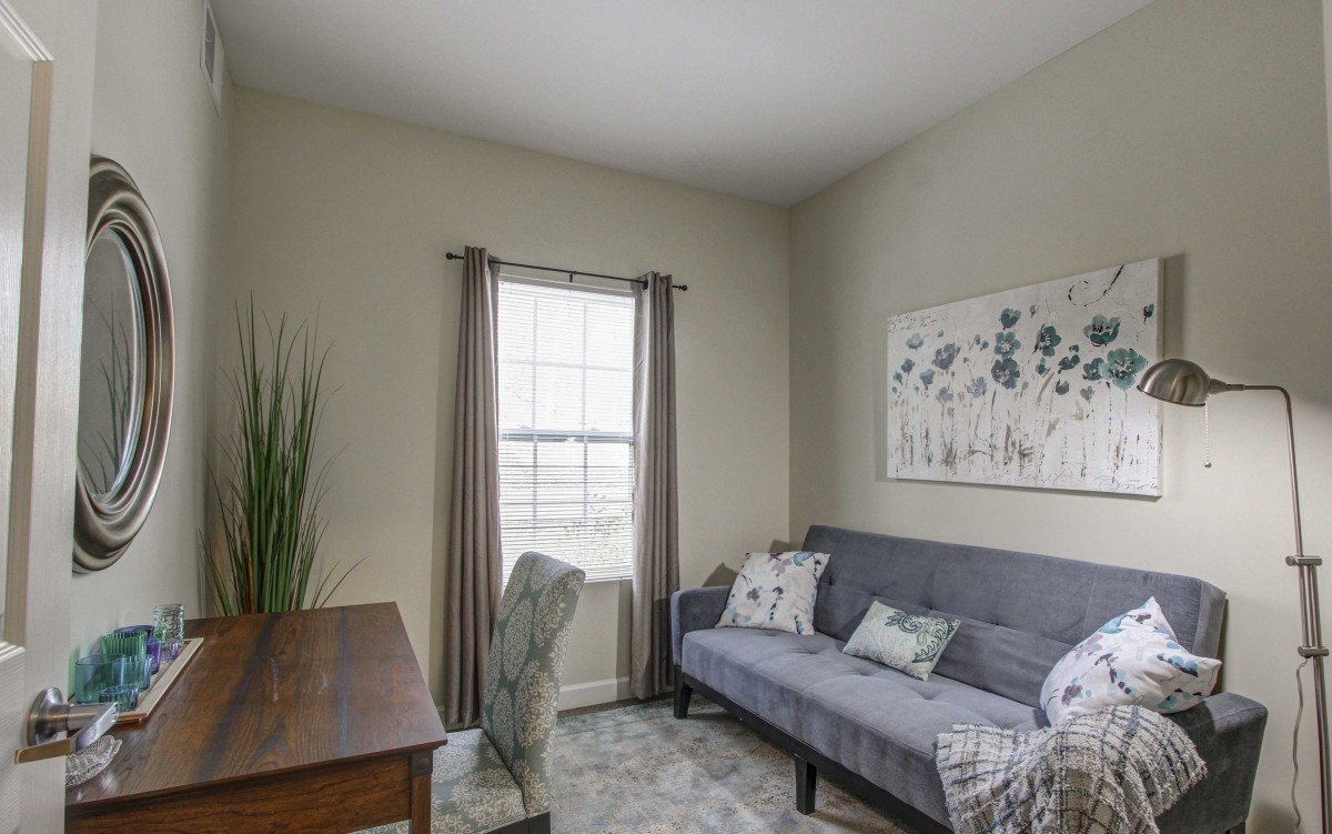 A cozy living room with a desk, sofa, and minimalist decor.