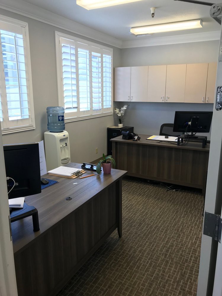 A neat and organized office space with two desks, computers, and a water dispenser.