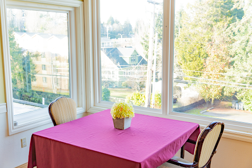 A bright and inviting dining area with a pink tablecloth and a floral centerpiece, showcasing a beautiful view through the windows.