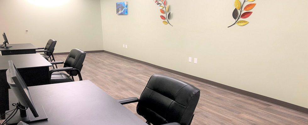 An empty office space with a black chair, a desk, and wall decorations.