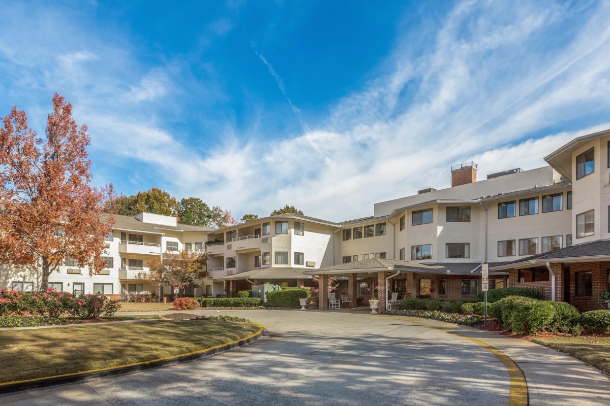 A sunny day view of a residential apartment complex with clear blue skies and scattered clouds.