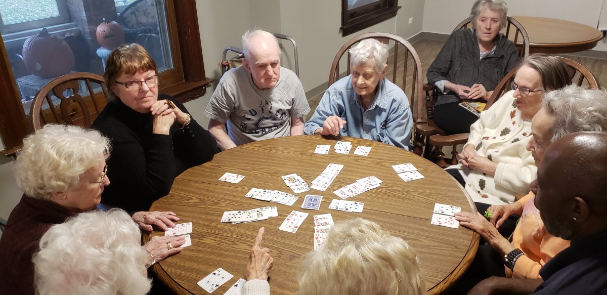 A group of seniors gathered around a table playing a card game together.