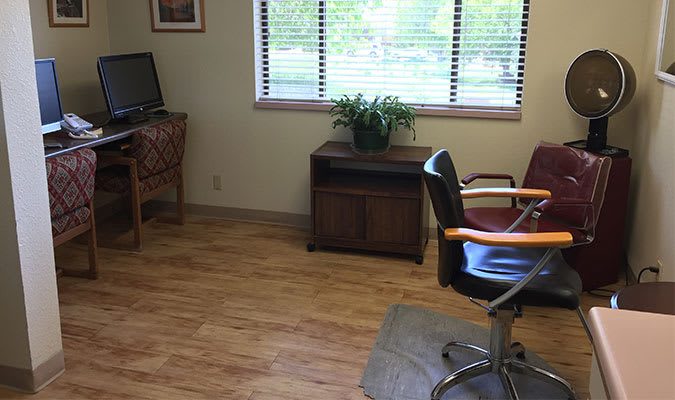 A small office space with a desk, chair, and plant by the window.