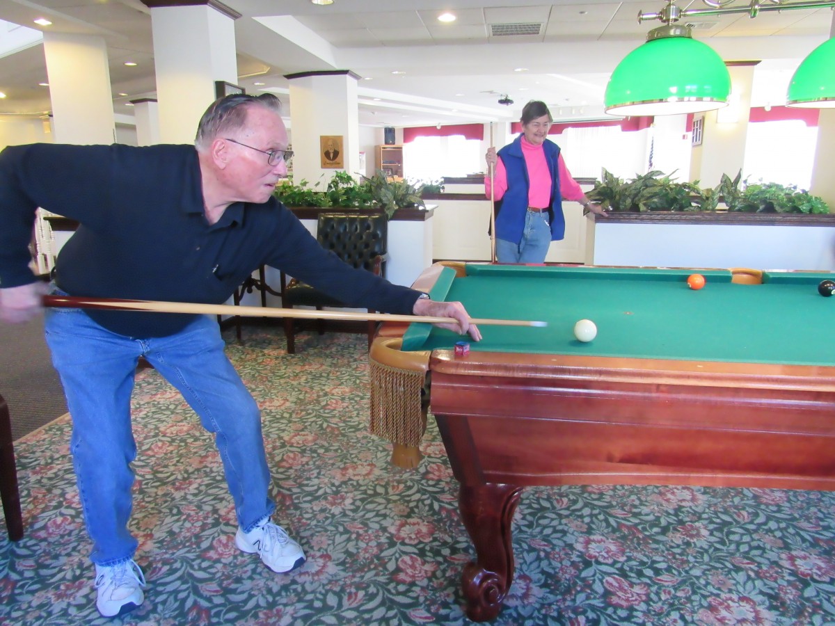 Two people playing a game of pool indoors.