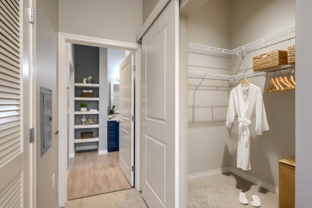A modern walk-in closet with a white bathrobe hanging and shelves in the background.