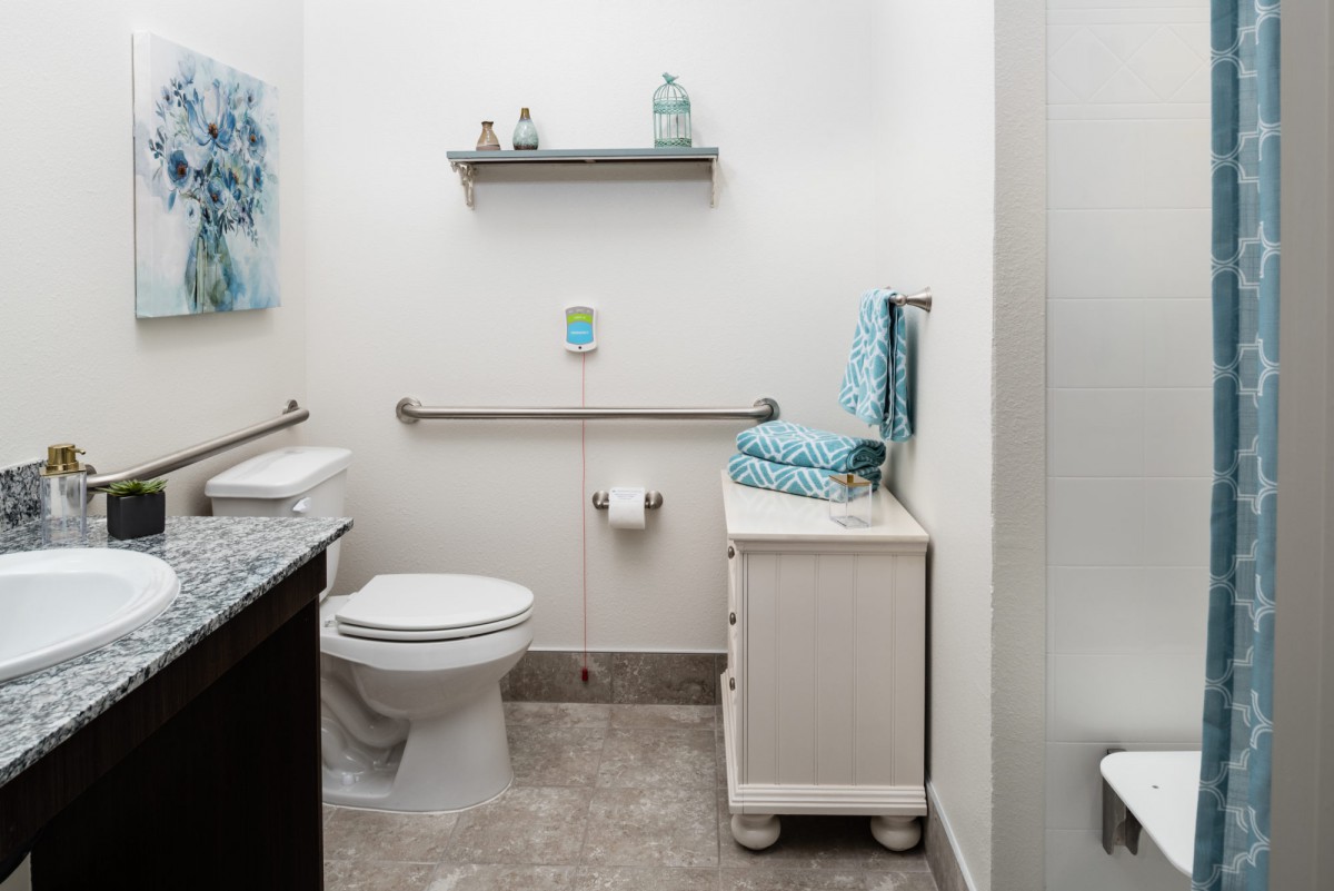 A neatly organized bathroom with a toilet, sink, and shelves stocked with towels and decor.