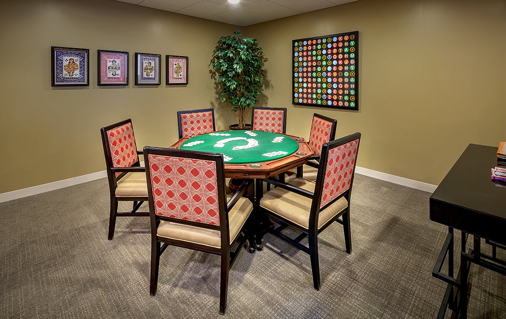 A stylish game room featuring a poker table with red-patterned chairs and themed decor.