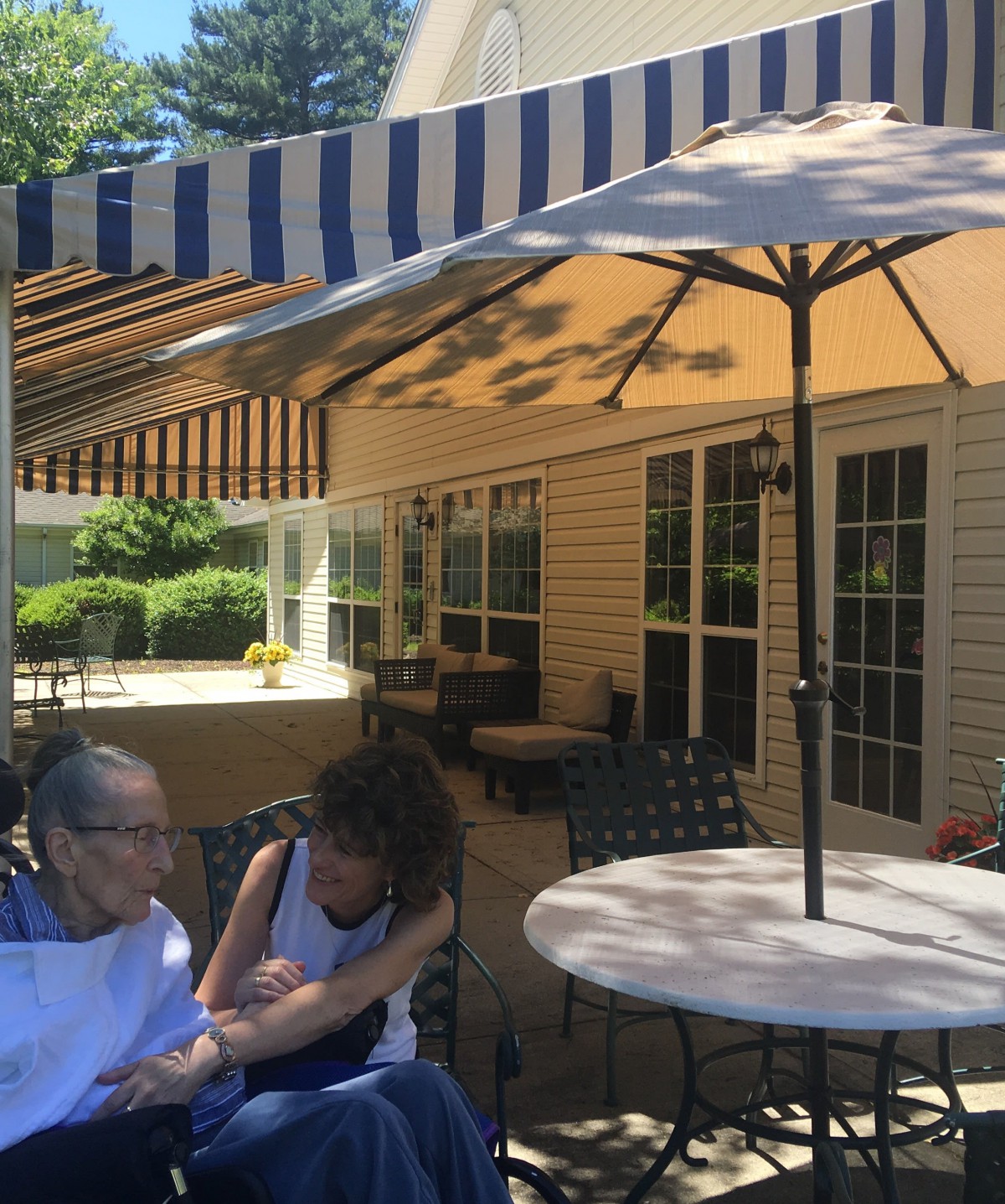 Two people enjoying a sunny day on a shaded patio.