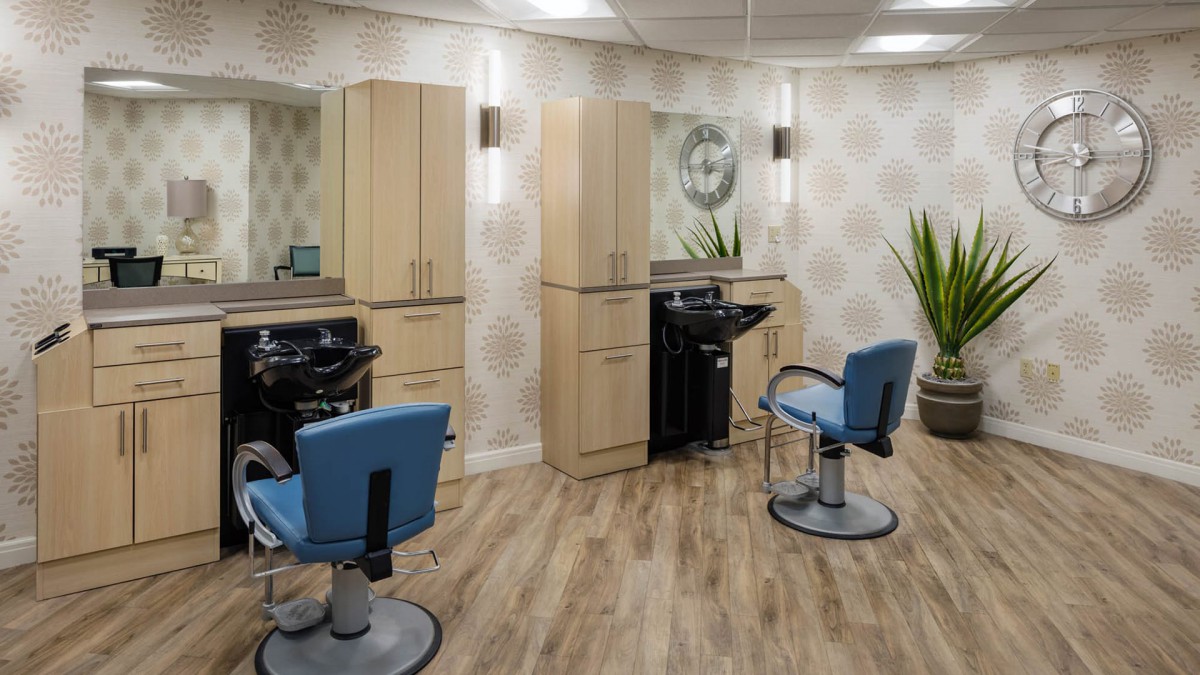 A modern hair salon interior with stylish chairs and mirrors, featuring wood flooring and sleek cabinetry.