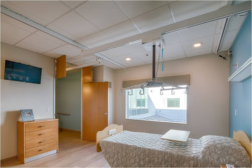 A modern hospital patient room featuring ample natural light and a minimalist design.