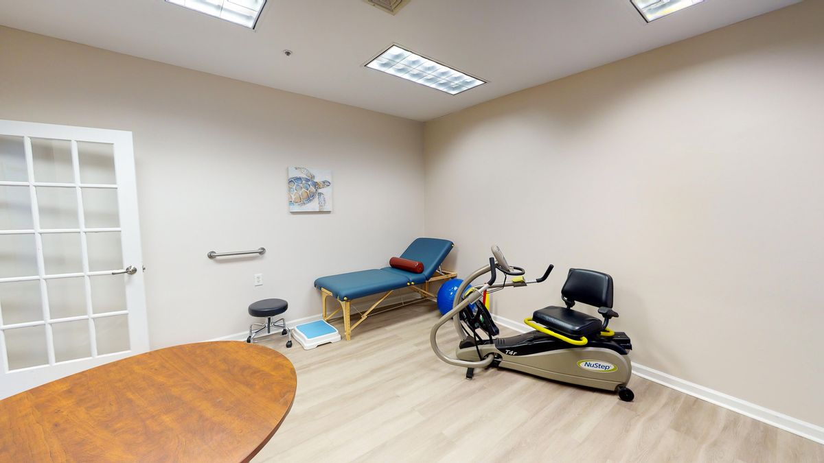 A medical room equipped with a therapy bed and an exercise bike.