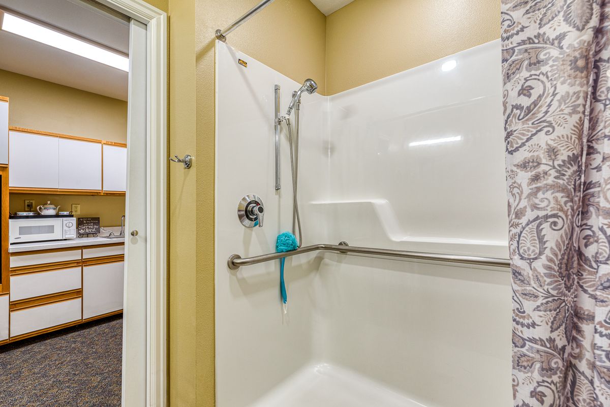 An accessible shower with a grab bar for safety and a handheld showerhead.
