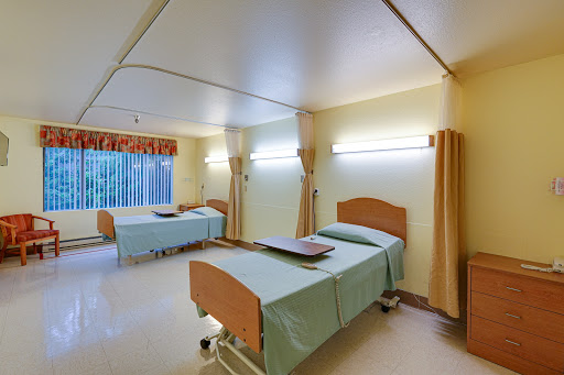 A well-lit hospital patient room featuring two beds and a calming environment.