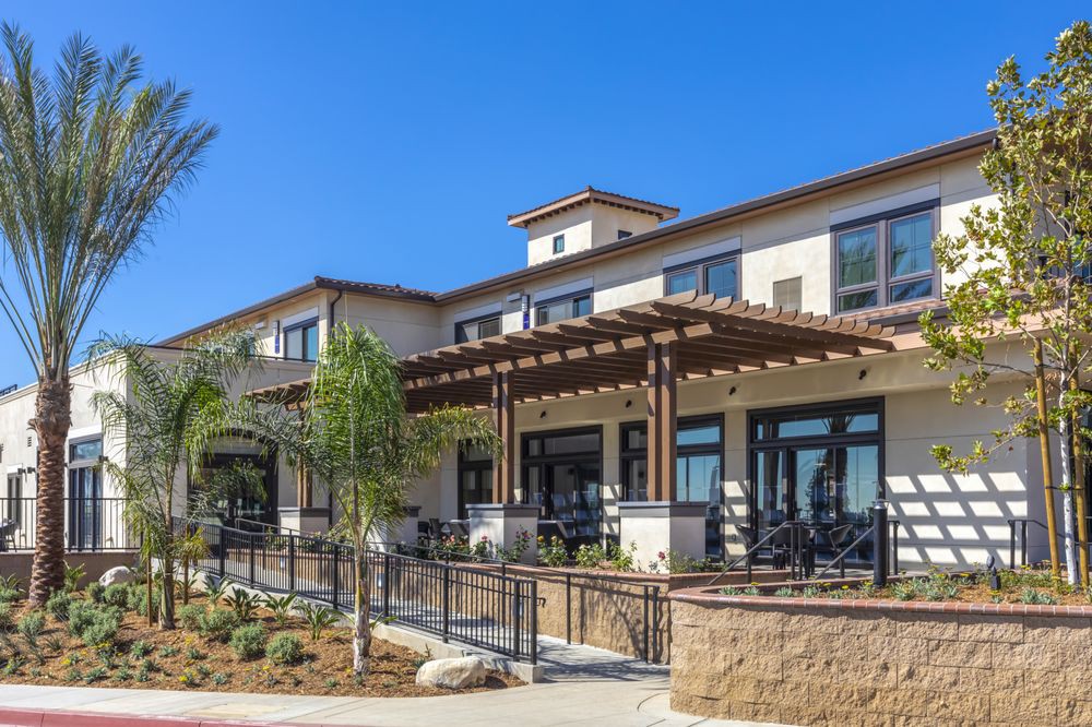 A modern commercial building with a patio and landscaped surroundings on a clear, sunny day.